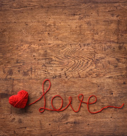The word "love" written of red wool yarn on wooden background. Top view. Valentines Day backgroundの写真素材