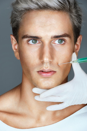 Beautiful Man getting Botox injection in the nasolabial folds. Professional cosmetician making rejuvenate injection. Beauty conceptの写真素材