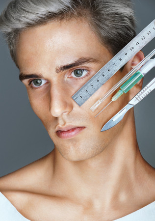 Beautiful man face. Portrait of young man with surgical instruments. Clean Beauty conceptの写真素材