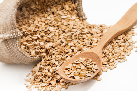 Close up raw oatmeal in wooden spoon and sack on white background. Close up, high resolution productの写真素材