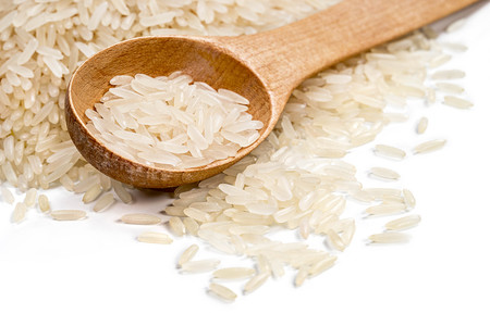 Close up of wooden spoon and parboiled rice scattered on white background. High resolution product. Healthy food conceptの写真素材