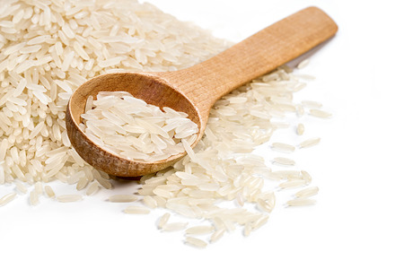 Pile parboiled rice and wooden spoon on white background. Close up, high resolution product. Healthy food conceptの写真素材