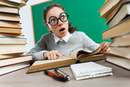 Thoughtful student looking away while sitting at the desk with open book. Education conceptの写真素材