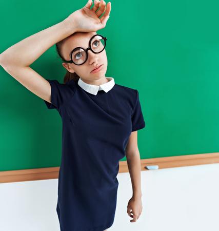 Tired student near the blackboard. Photo of a smart student in uniform, education concept. Copy space for your textの写真素材