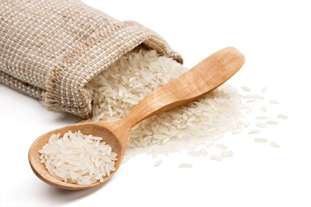 Parboiled rice  in wooden spoon and sack with scattered rice on white background. Close up, high resolution productの写真素材