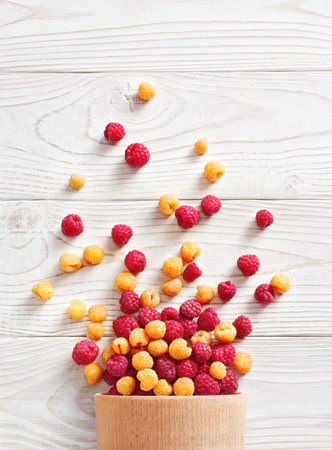 Raspberry explosion. Photo of raspberry in bowl on white wooden table. Top view. High resolution...