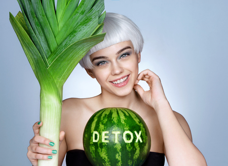 Pretty girl with green leek and watermelon. Photo of smiling blonde girl on blue background. Detox conceptの写真素材