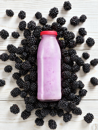 Blackberry around bottle of yogurt on wooden table. Fresh yogurt. Healthy food concept. High resolution product. Top viewの写真素材