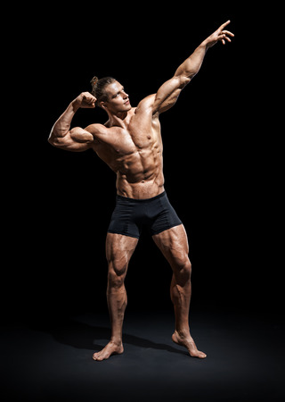Athletic man posing. Photo of man with perfect physique on black background. Strength and motivationの写真素材
