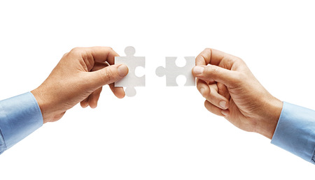 Two men's hands in shirt connecting jigsaw puzzle isolated on white background. Close up. High resolution productの写真素材