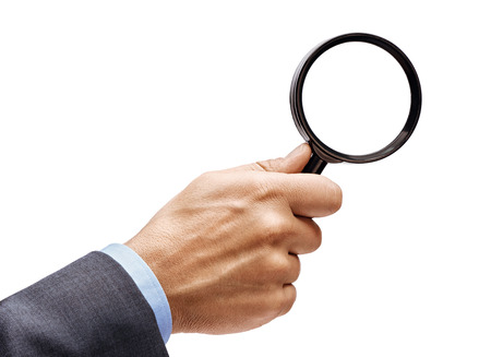 Man's hand in suit holding magnifying glass isolated on white background. Close up. High resolution productの写真素材