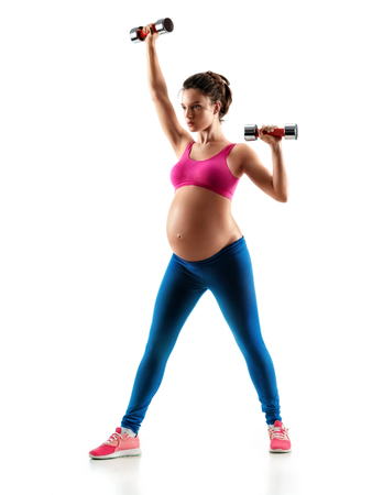 Sporty pregnant woman training muscles of hands using a dumbbells isolated on white background. Concept of healthy lifeの写真素材