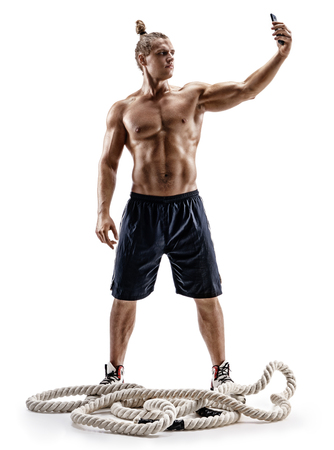 Strong man taking selfie on smartphone after workout. Photo of man with naked torso isolated on white background. Strength and motivation. Full lengthの写真素材