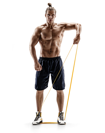 Man with athletic body performs exercises using a resistance band. Photo of muscular man isolated on white background. Strength and motivation. Full lengthの写真素材