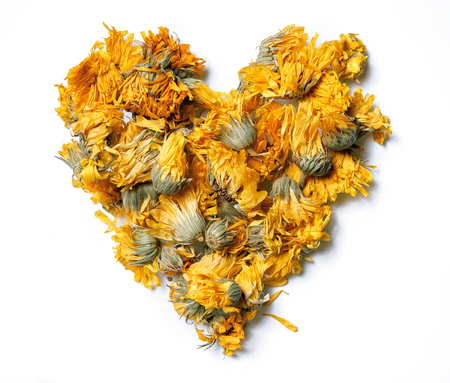 Heart shaped from medicinal flowers of a calendula isolated on white background. Herbal tea. Top view. Close up. High resolution