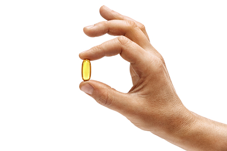 Man's hand holding Omega 3 capsule isolated on white background. Close up. High resolution product.