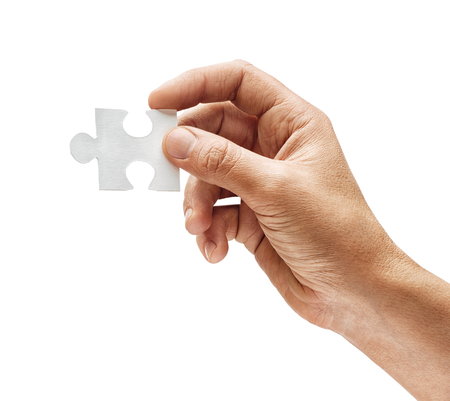 Man's hand holding one puzzle element isolated on white background. Close up. High resolution productの写真素材