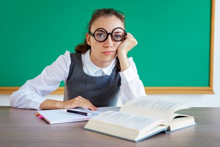 Exhausted or bored young student in classroom. Photo of student wearing glasses. Education conceptの写真素材