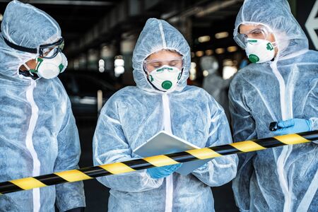 Team of healthcare workers wearing hazmat suits working together to control an outbreak in the cityの写真素材