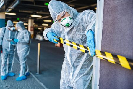 Healthcare worker cordoning off an urban area with barrier tape during an outbreakの写真素材