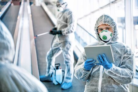 Healthcare workers wearing hazmat suits working together in shopping centre, to control an outbreak of virus in the cityの写真素材