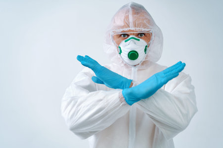 Healthcare worker in protective suit and medical mask showing stop gesture, to control an outbreak...