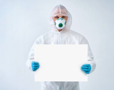 Healthcare worker in protective suit and medical mask holds empty copy space. Health care concept.の写真素材