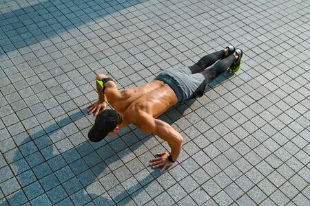 Strong man does push-ups. Photo of young man workout along outdoor in the cityの写真素材