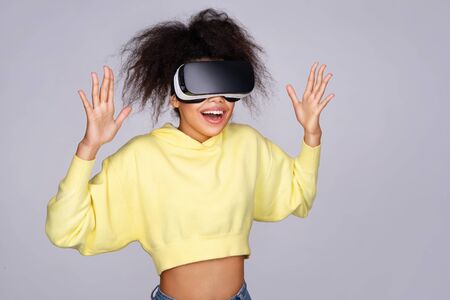 Happy girl with glasses of virtual reality on grey backgroundの写真素材