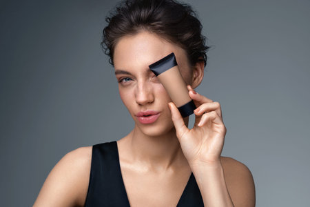 Woman with liquid foundation. Photo of woman with perfect makeup on gray background. Beauty concept
