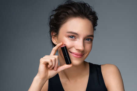 Woman with lipstick. Photo of woman with perfect makeup on gray background. Beauty conceptの写真素材