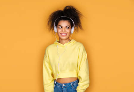 Funny girl in headphone, listens music on yellow backgroundの写真素材