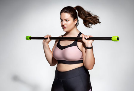 Sporty girl doing exercises with body bar. Photo of model with curvy figure in fashionable...