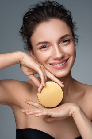 Woman holds jar with cosmetic cream. Photo of attractive woman with perfect makeup on gray...