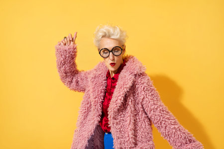 Happy and playful mature woman dancing, smiling and having fun. Photo of elderly woman over 70 years...