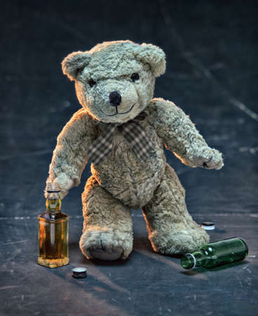 The Teddy bear symbolizing a child. Drunk teddy bear drinking whiskey alone. Children's alcoholismの写真素材