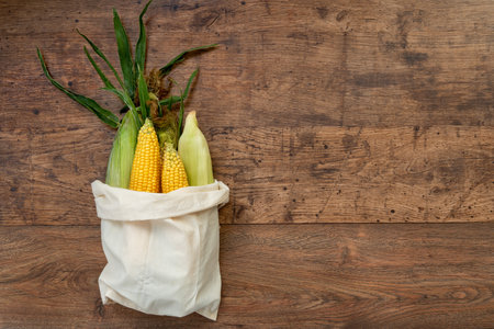 Corns in woven bag on old wooden tableの写真素材