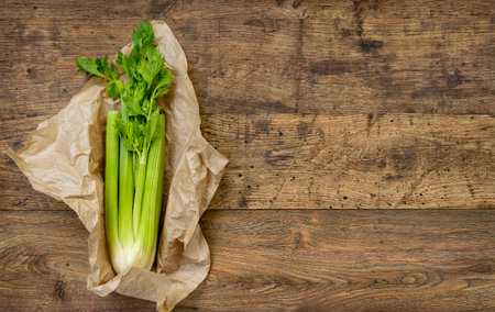 Celery in paper packaging on old wooden tableの写真素材