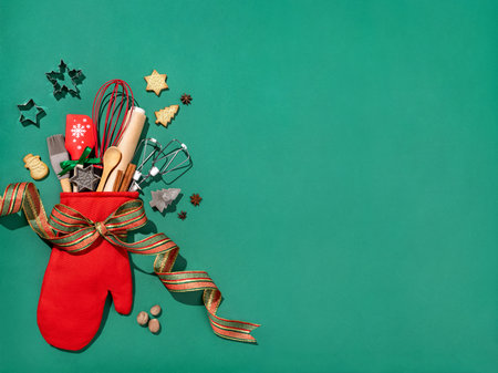 Christmas red oven-glove with kitchen utensils for homemade baking on green background. Merry Christmas and Happy New Year concept. Copy space for your text. View from aboveの写真素材