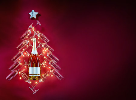 Silhouette of celebratory tree, a bottle of champagne surrounded by glasses and stars on red background. Merry Christmas and Happy New Year conceptの写真素材
