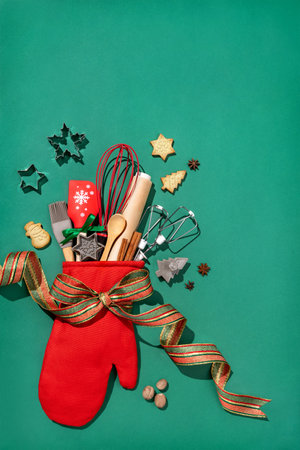 Christmas red oven-glove with kitchen utensils for homemade baking on green background. Merry Christmas and Happy New Year concept. Copy space for your text. View from aboveの写真素材