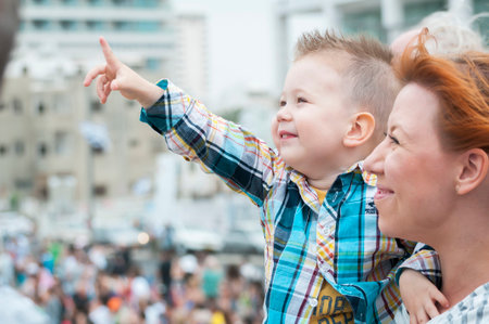 Child and his mother watching the air show dedicated to Israel's Independence Day in the Tel Aviv promenade. Yom Ha'Atzmaut stock image. Tel Aviv, Israel, May 2014.のeditorial素材