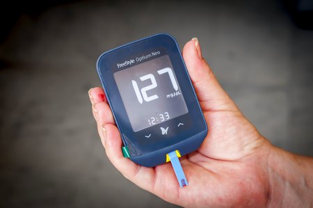 Woman patient with pregnancy diabetes holding in her hands a Freestyle Optium Neo glucometer after the blood testing with high glucose level results. Pregnancy diabetes stock image.の素材 [FY310104079051]