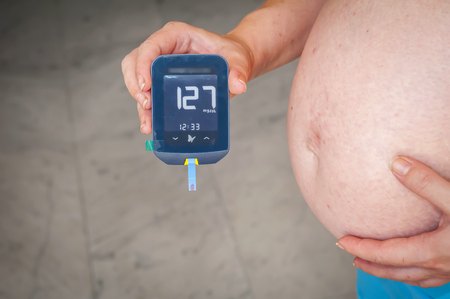Woman patient with pregnancy diabetes holding in her hands a Freestyle Optium Neo glucometer after the blood testing with high glucose level results. Pregnancy diabetes stock image.の写真素材