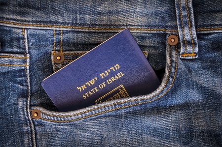 A blue passport of the State of Israel sticking from a pocket of blue denim jeans. Israeli tourist travel, Israel citizenship concept, Israeli biometric (darkon) passport illustrative image. See the worldの写真素材