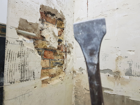 a drill from a perforator, a chisel and a strobe in a brick wall and a propylene pipe - plumbing in the bathroomの写真素材