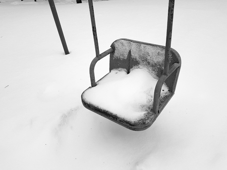 Children playground near the house in the winter in the snow - swingの写真素材
