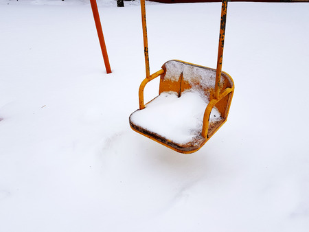 Children playground near the house in the winter in the snow - swingの写真素材