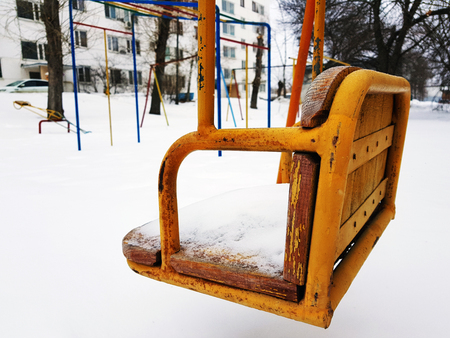 Children playground near the house in the winter in the snow - swingの写真素材