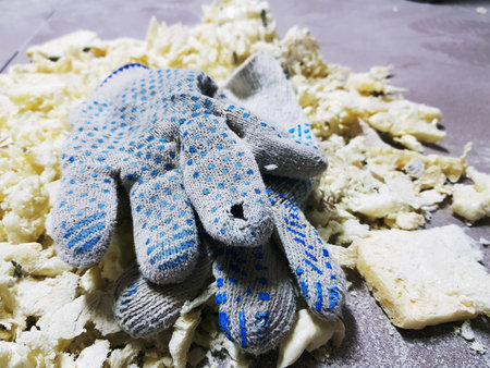 Repair and construction waste - trimming foam and building gloves on the tiled floor